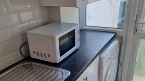 Una cocina con microondas, lavabo y lavadora.