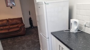 Una cocina compacta con un refrigerador blanco, una encimera negra y un taburete negro.