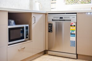 Eine kompakte Küche mit integriertem Geschirrspüler, Kühlschrank und Mikrowelle.