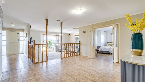 A spacious hotel lobby with a wooden railing, a large vase with yellow flowers, and a view into a bedroom area. - StayAU Tranquil 4BR Lakeside Retreat in Seabrook (Seabrook)