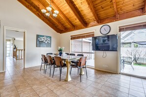 Un espace repas doté d’un plafond en bois, d’une grande fenêtre et d’un téléviseur à écran plat.