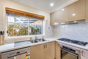 A modern kitchen with a gas stove, double sink, and built-in oven.