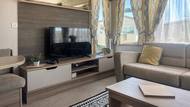 En moderne stue med et fladskærms-tv, en sofa, et sofabord og et spiseområde.