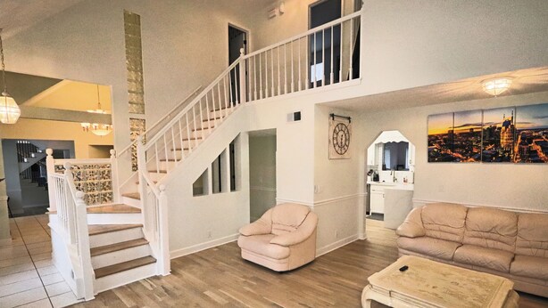 A spacious living area with a wooden floor, a staircase, a beige armchair, a sofa, and a coffee table. - THE BIG HOUSE ~ With 620 sq ft EVENT SPACE ~ (view on YouTube "The Big House")
 (Nashville)