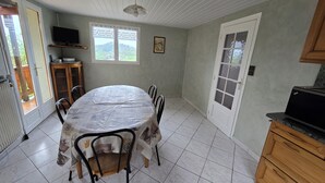 A dining area with a round table, chairs, a television, and a view of the outdoors.