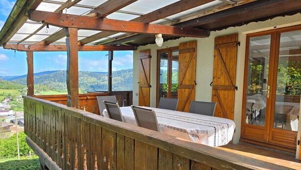 A wooden deck with a table and chairs, overlooking a scenic landscape.