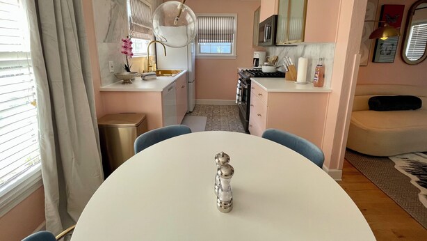 Une cuisine compacte équipée d’un évier, d’une cuisinière et d’un four à micro-ondes. On aperçoit une table à manger avec des chaises au premier plan.