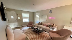 Un salon avec un canapé beige, deux fauteuils, une table basse et un tapis à motifs.