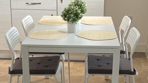 Une cuisine moderne avec des meubles blancs, un micro-ondes encastré et une table à manger avec quatre chaises.