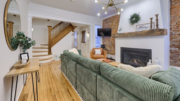 A living room with a green sofa, a wooden coffee table, a fireplace, and a staircase. - Cityside on North Prince, in Historic Downtown Lancaster (Lancaster)