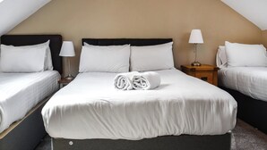 A hotel room with a sloped ceiling, two beds with white linens, a rolled towel on the bed, and two bedside lamps. - 3 bedroom accommodation in Llanilar, near Aberystwyth (Llanilar, near Aberystwyth)