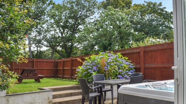 A patio area with a hot tub, outdoor seating, and a wooden fence. - 3 bedroom accommodation in Llanilar, near Aberystwyth (Llanilar, near Aberystwyth)