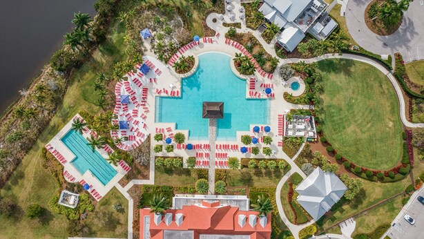 An aerial view of a resort with a central swimming pool, multiple lounge areas, and a parking lot. - New 2 Bedroom + Den, 2 Bath Home w/2 Car Garage 10 Min from Downtown Naples (Naples)