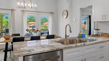 A modern kitchen with a marble countertop, stainless steel appliances, and a dining area with a view of the outdoors.