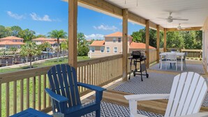 A covered outdoor area with wooden deck, two Adirondack chairs, a grill, and a table. - New, August 2024! Beautiful porch, view of Marina (Homosassa)