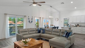 A spacious living area with a large L-shaped sectional sofa, a wooden coffee table, and a ceiling fan. - New, August 2024! Beautiful porch, view of Marina (Homosassa)