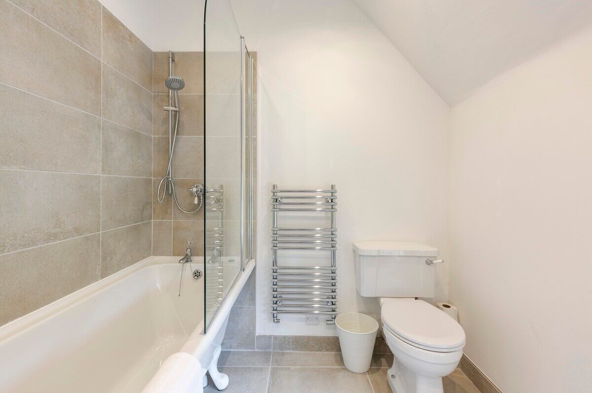 Un baño con bañera, ducha, inodoro y toallero.