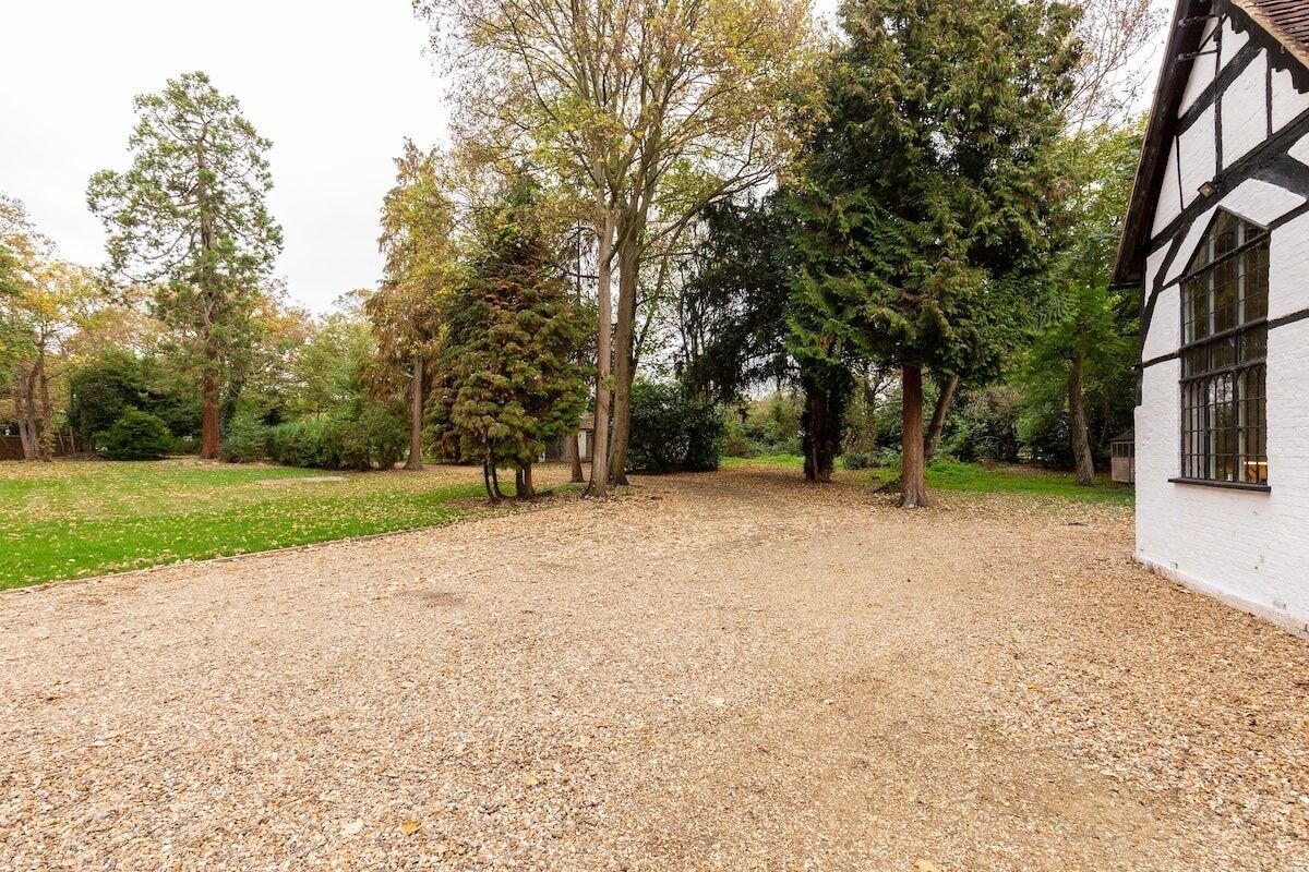 Une allée de gravier mène à un bâtiment blanc dont la structure est en bois foncé.