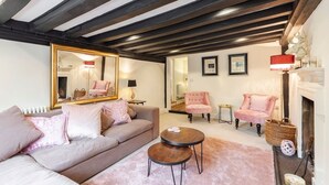 Een knusse woonkamer met een bank, een ronde salontafel, een open haard en een spiegel.