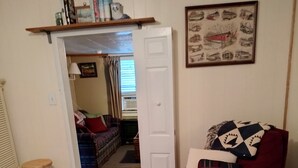 Una habitación acogedora con un sillón rojo, un tapete estampado, una cama y una estantería.
