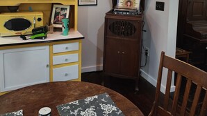 Un coin repas avec une table dressée pour deux personnes, une radio et un vase décoratif.
