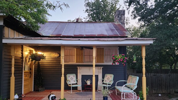 Une maison à deux étages avec un porche, une pancarte de bienvenue et un chien.