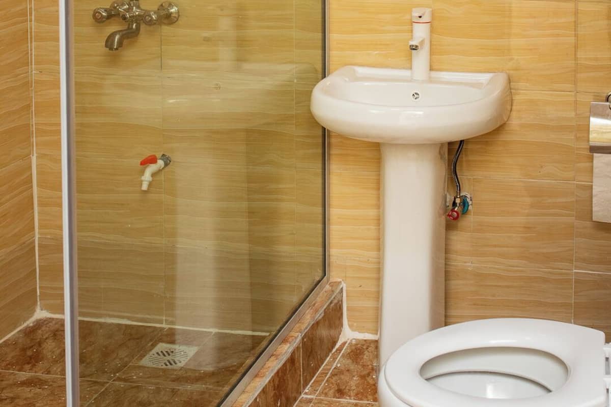 Kylpyhuone, jossa on lasiseinällä varustettu suihku, valkoinen pesuallas ja wc.
