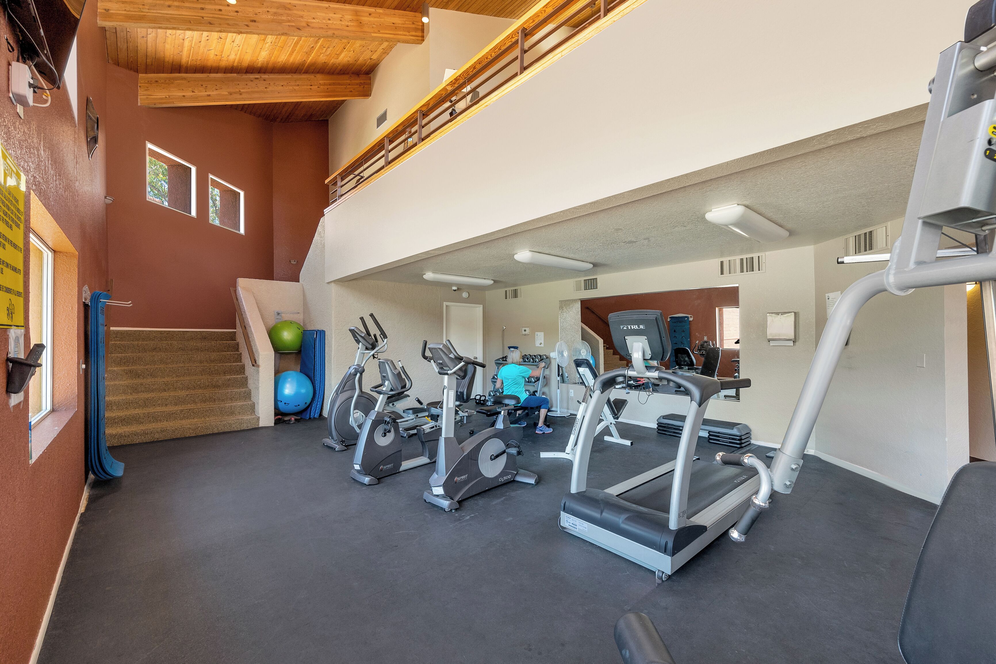 Une salle de sport équipée de tapis de course, de vélos d’appartement et de ballons d’exercice.
