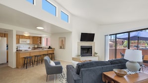 A spacious living area with a grey sofa, a wooden coffee table, and a kitchen with wooden cabinets and a built-in microwave. - Charming one bedroom in a gated community near Sabino Canyon with heated pool. (Tucson)