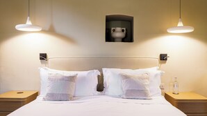 Ein Hotelzimmer mit einem Bett, zwei Nachttischen, einer Wandleuchte und einem kleinen Gegenstand an der Wand.
