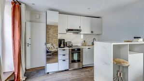 A compact kitchen with white cabinets, a built-in oven, and a coffee maker.