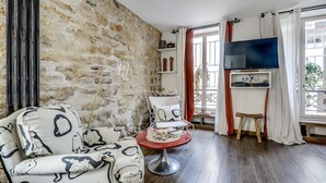 A cozy living room with a stone wall, a TV, a sofa, a chair, and a small table.