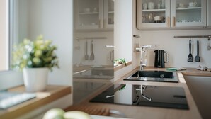 A modern kitchen with a central island, stainless steel appliances, and a window with a view of the outdoors.