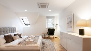 A modern bedroom with a large bed, a desk, and a chair.