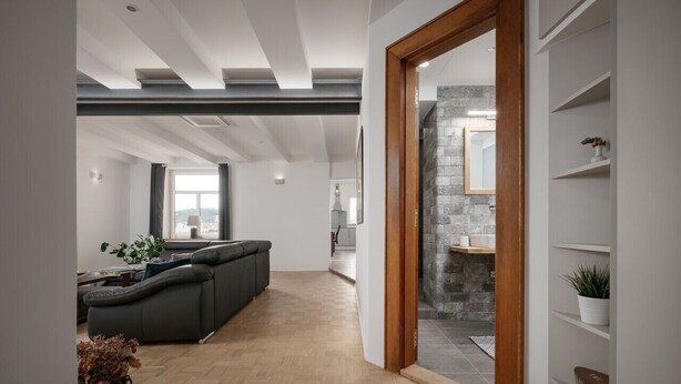 A modern living room with a sofa, wooden flooring, and a stone fireplace.