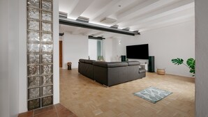 A modern living room with a sectional sofa, a flat-screen TV, and a large window.