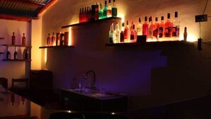 Un espace bar avec des étagères remplies de bouteilles d’alcool et un évier.