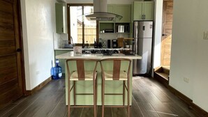 A kitchen with a central island, green cabinets, stainless steel appliances, and a wooden door.