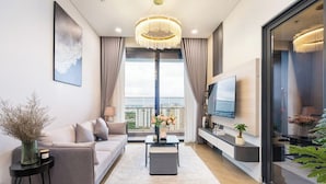 Una sala de estar moderna con un sofá, una mesa de centro, televisor y ventanas amplias.