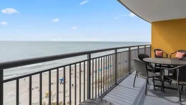 A balcony with a view of the sea, a table with chairs, and a yellow wall. - Oceans Crest! Oceanfront View Pools Putt Putt Spa (Myrtle Beach)