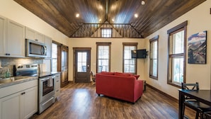 A spacious kitchen with modern appliances, a red sofa, and a dining area with a wooden table and chairs.