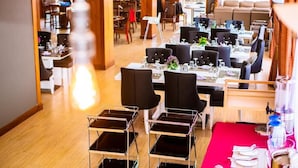Un restaurante con varias mesas y sillas, una alfombra roja y una vista del salón comedor al fondo.
