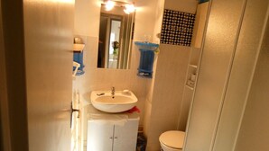 A compact bathroom with a sink, mirror, and toilet.