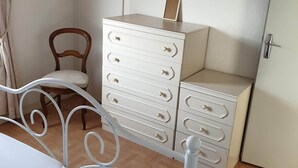 A bedroom with a bed, a dresser, a chair, and a mirror.