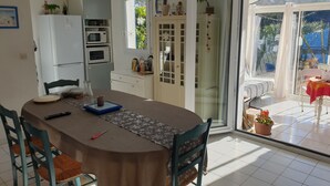 A dining area with a table, chairs, and a kitchen in the background.