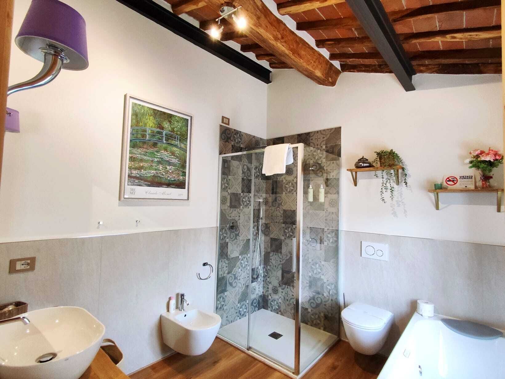Een badkamer met een bidet, toilet, douche met glazen deuren en een wastafel.
