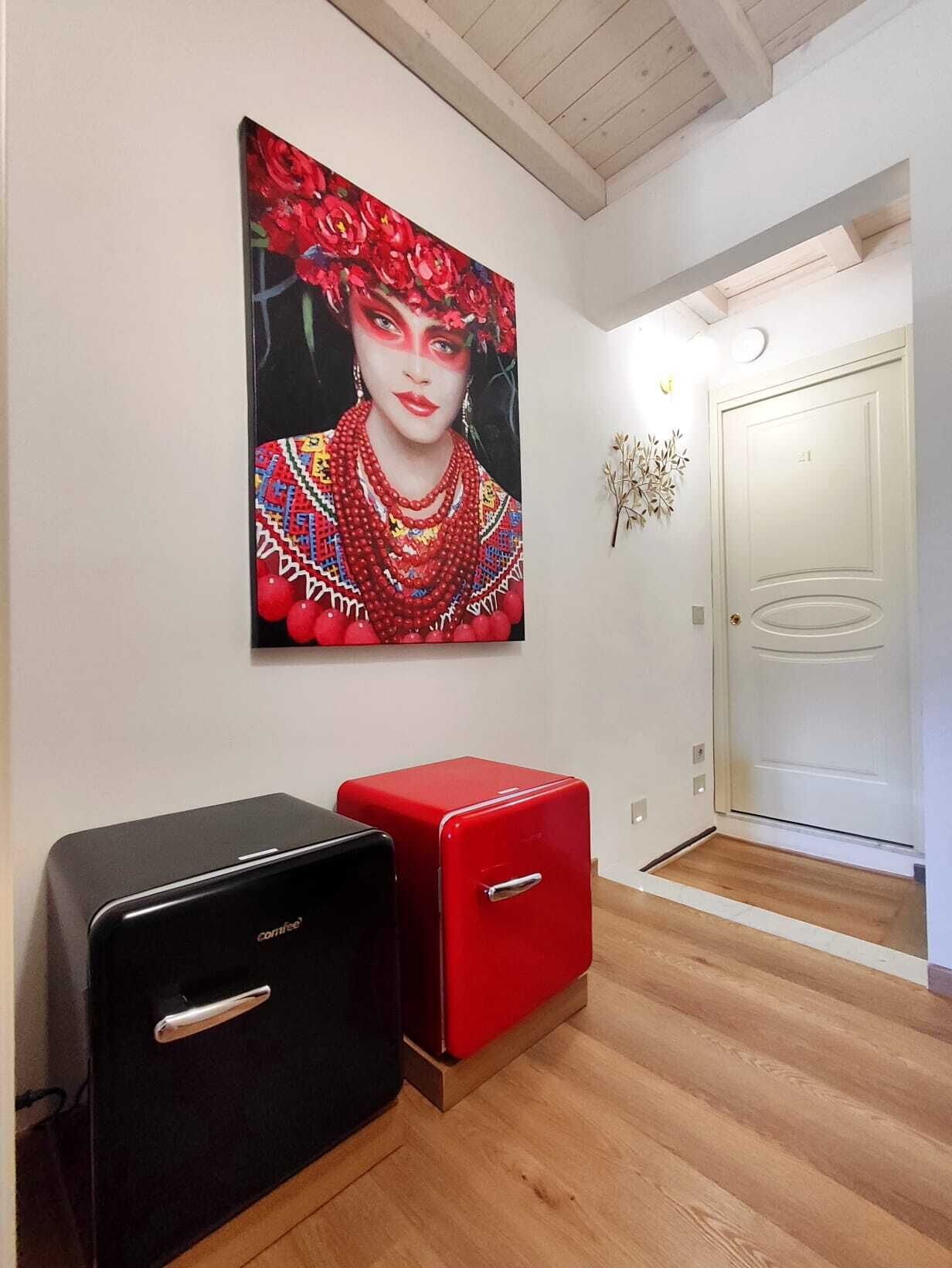 A hallway with a modern door, a red and black storage unit, and a vibrant painting on the wall.