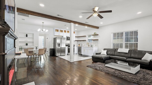 A modern living room with a sectional sofa, a glass coffee table, and a dining area with a white table and chairs.