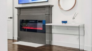 A modern interior with a fireplace, a mounted television, and a glass display cabinet.