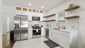 A modern kitchen with white cabinetry, stainless steel appliances, and geometric backsplash tiles.